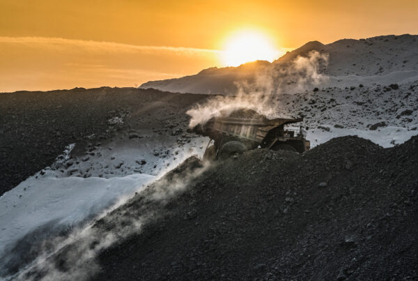 A photo of a mining truck set against slopes and a sunset.