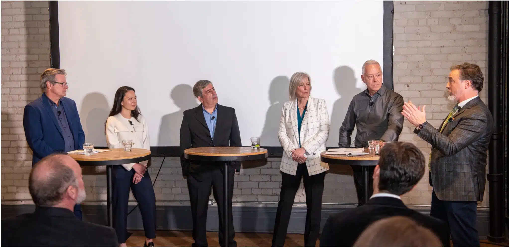 A photo of 6 presenters casually standing in front of a projector screen