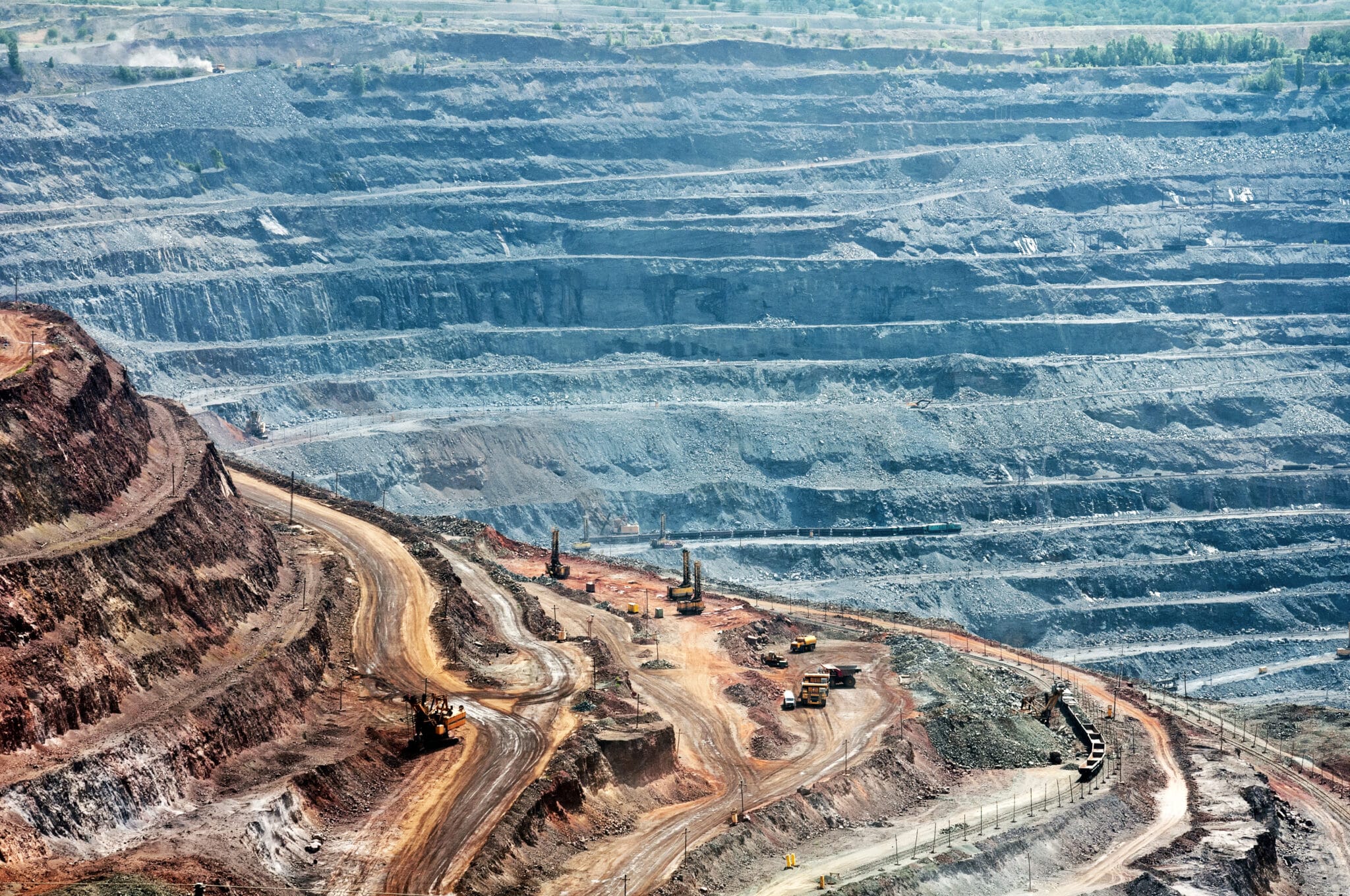 close up of quarry extracting iron ore with heavy trucks, excavators, diggers and locomotives